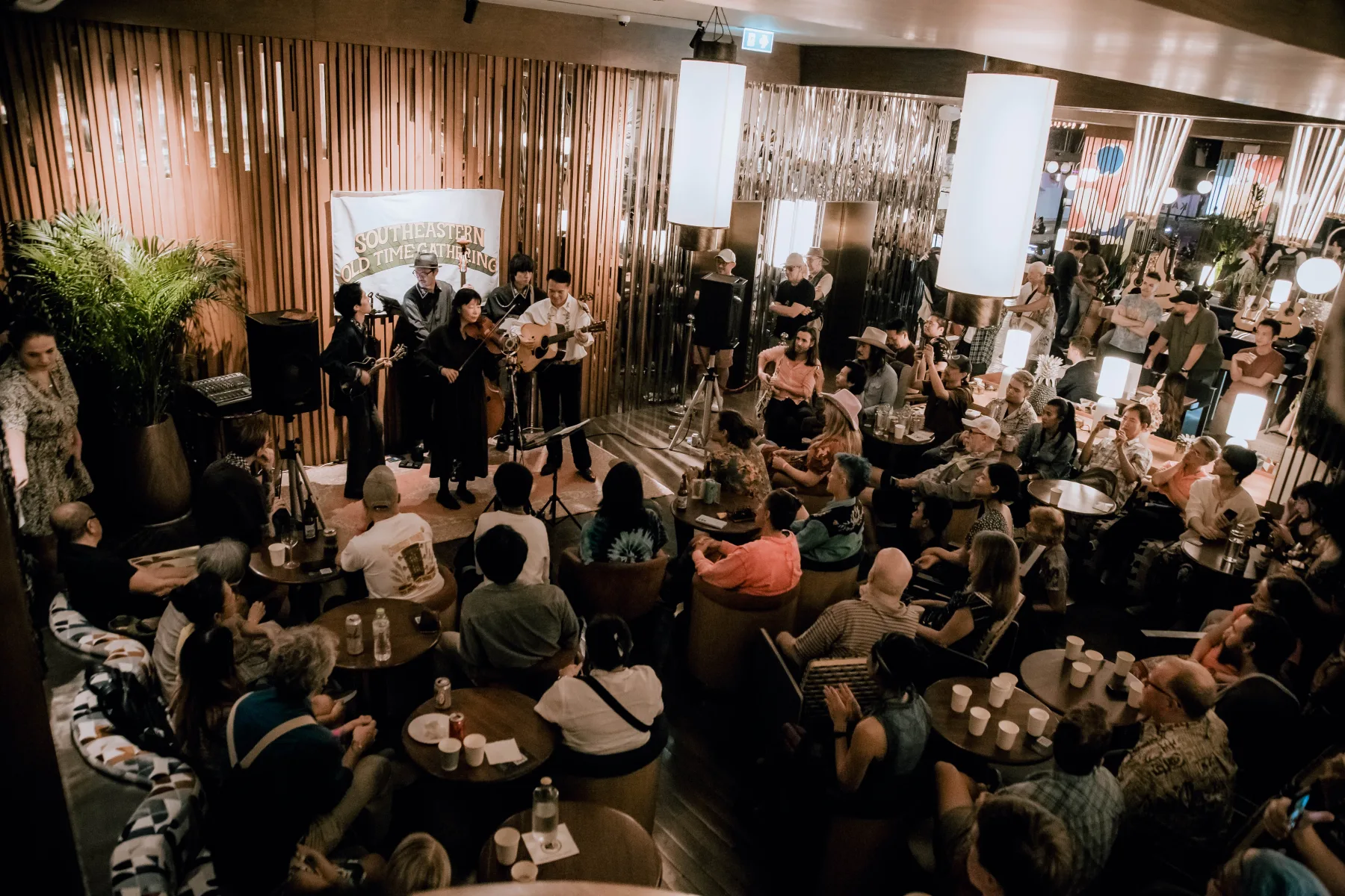 Elevated view over a room packed with musicians and listeners